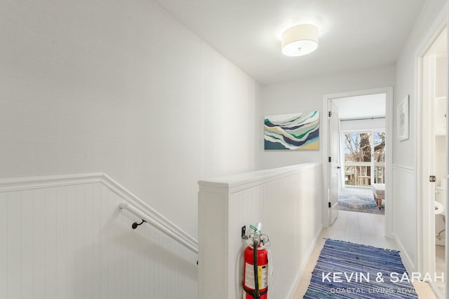 corridor with wainscoting and an upstairs landing