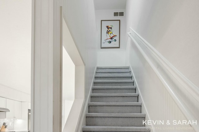 staircase featuring a wainscoted wall and visible vents