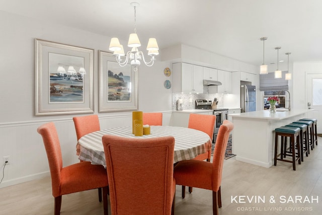 dining space with a chandelier, wainscoting, and light wood finished floors