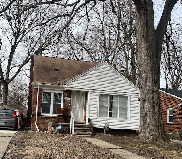 view of front of home with roof with shingles and brick siding