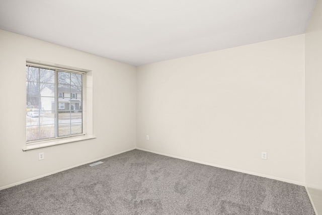 spare room with carpet, visible vents, and baseboards