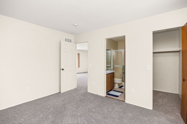 unfurnished bedroom featuring carpet floors, visible vents, a spacious closet, and baseboards