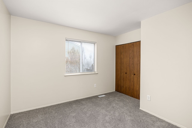 unfurnished bedroom featuring baseboards, carpet, visible vents, and a closet