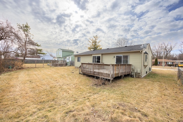 back of property with a yard, fence, and a wooden deck