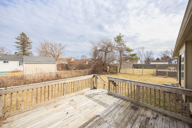 wooden terrace featuring an outdoor structure, a lawn, and fence