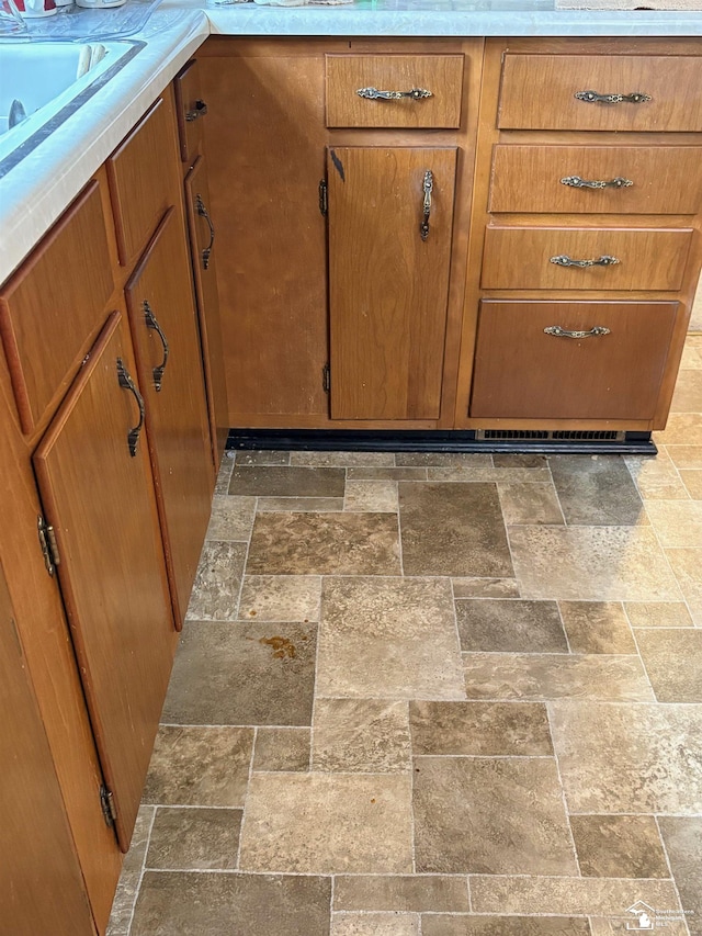 interior details with a sink, brown cabinetry, and light countertops