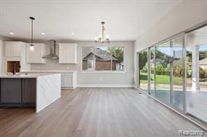 kitchen with white cabinetry, light countertops, a sink, and exhaust hood