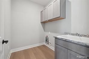 washroom featuring cabinet space, baseboards, dark wood finished floors, hookup for an electric dryer, and a sink