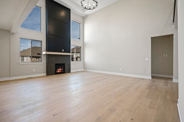 35689 Windridge Dr, New Baltimore, MI 48047 - unfurnished living room with an inviting chandelier, a high ceiling, light wood-style flooring, and a wealth of natural light