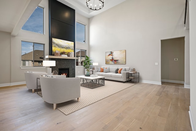 35689 Windridge Dr, New Baltimore, MI 48047 - living area with a lit fireplace, light wood-type flooring, baseboards, an inviting chandelier, and a high ceiling