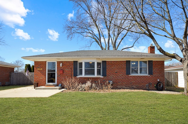 view of front facade with brick siding, a chimney, a front lawn, and fence