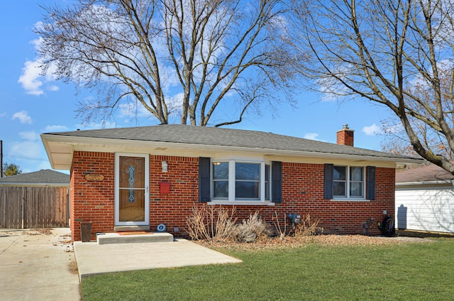 view of front of house with fence, roof with shingles, a front yard, brick siding, and a chimney