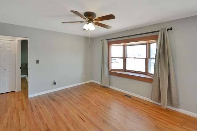 spare room with ceiling fan, visible vents, baseboards, and light wood-style flooring