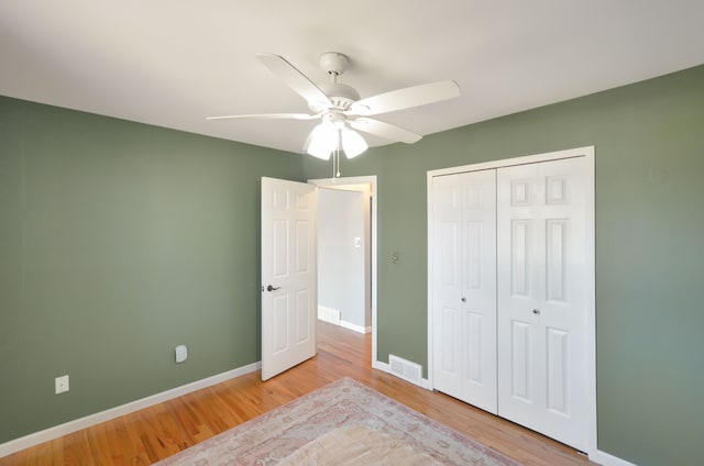 unfurnished bedroom with a closet, visible vents, baseboards, and wood finished floors