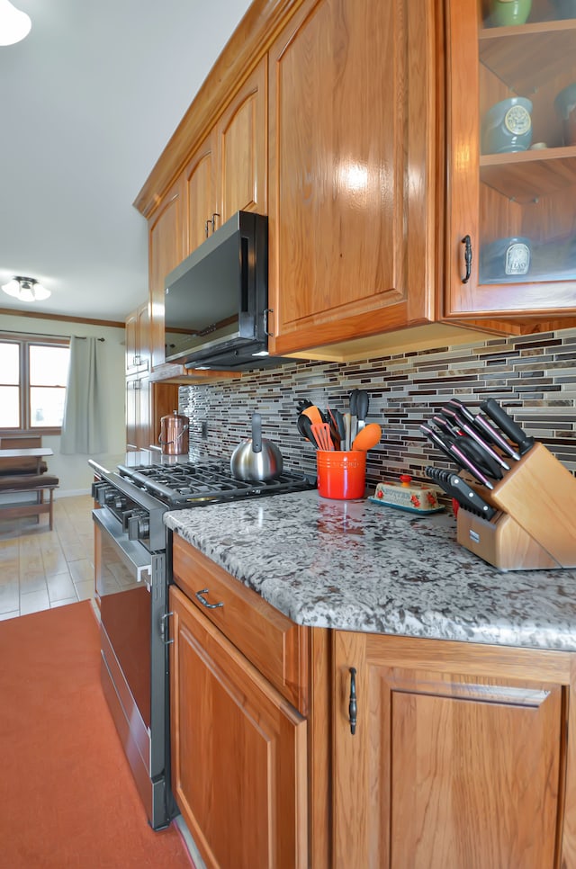 kitchen with gas stove, light stone countertops, and tasteful backsplash