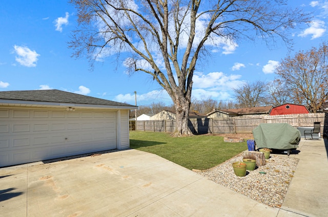 view of yard featuring a garage, an outbuilding, and fence