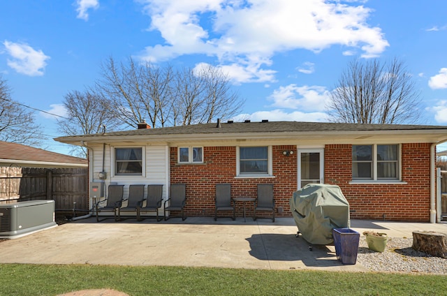 back of property with fence, brick siding, a chimney, and a patio area