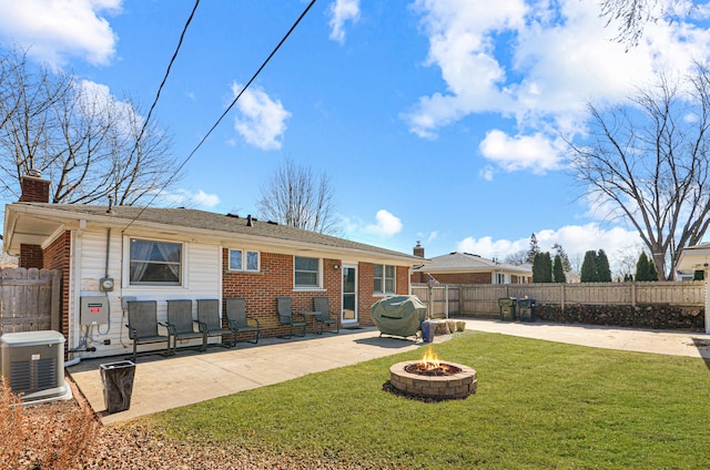 back of house with a patio, a chimney, a fire pit, a lawn, and brick siding