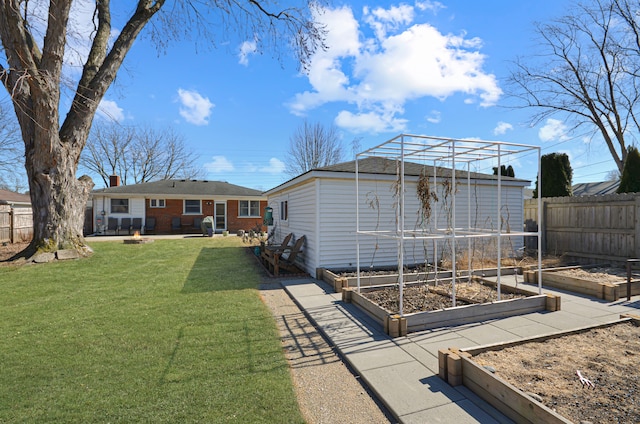 view of yard with an outbuilding, fence, and a garden