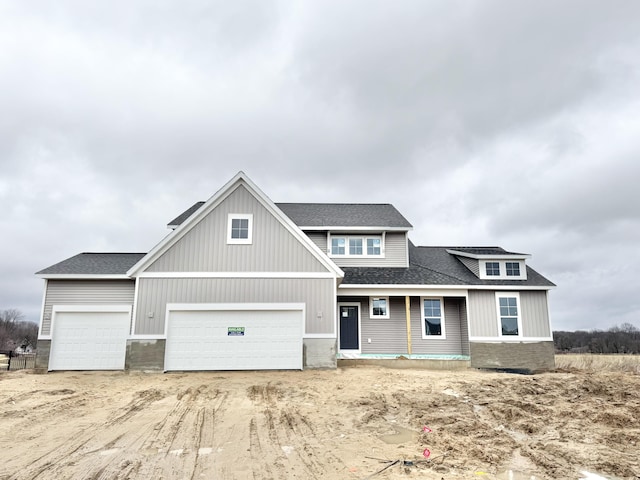 view of front of property with a shingled roof, an attached garage, and dirt driveway