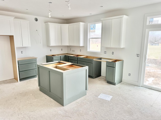 kitchen with plenty of natural light, white cabinetry, baseboards, and a center island