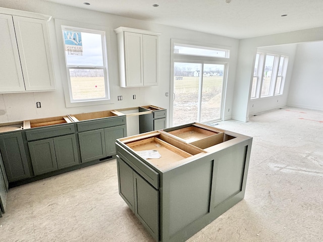 kitchen featuring baseboards, white cabinets, green cabinetry, and a center island