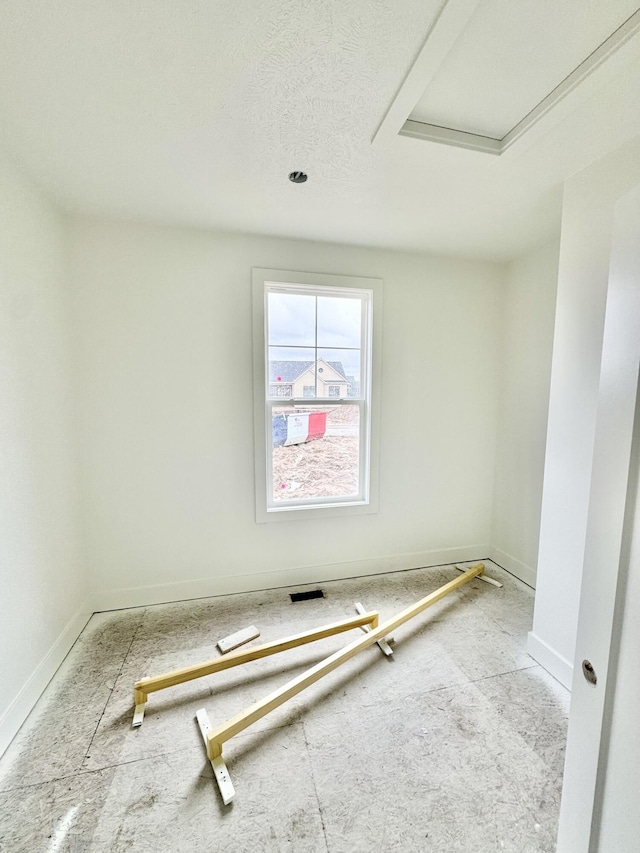 spare room with a textured ceiling and baseboards