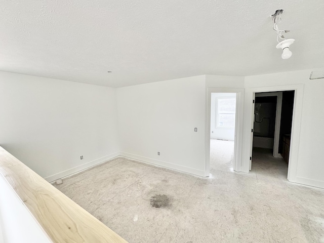 unfurnished room with a textured ceiling and baseboards