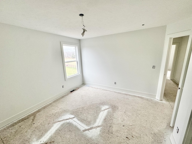 spare room with baseboards and a textured ceiling