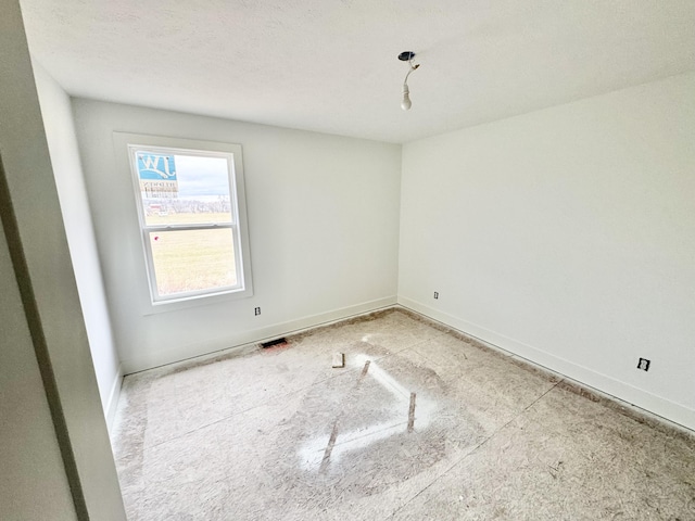 unfurnished room featuring a textured ceiling and baseboards