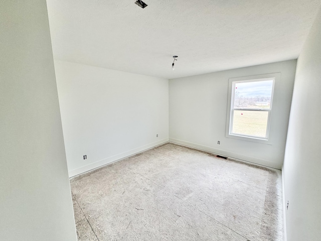 unfurnished room featuring visible vents, a textured ceiling, and baseboards