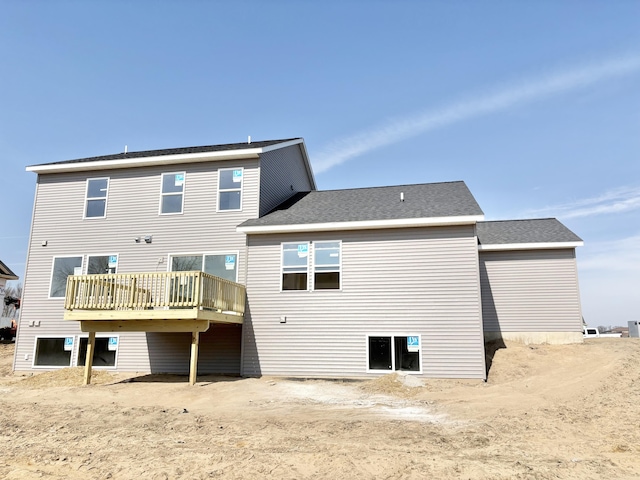 back of house with roof with shingles and a deck