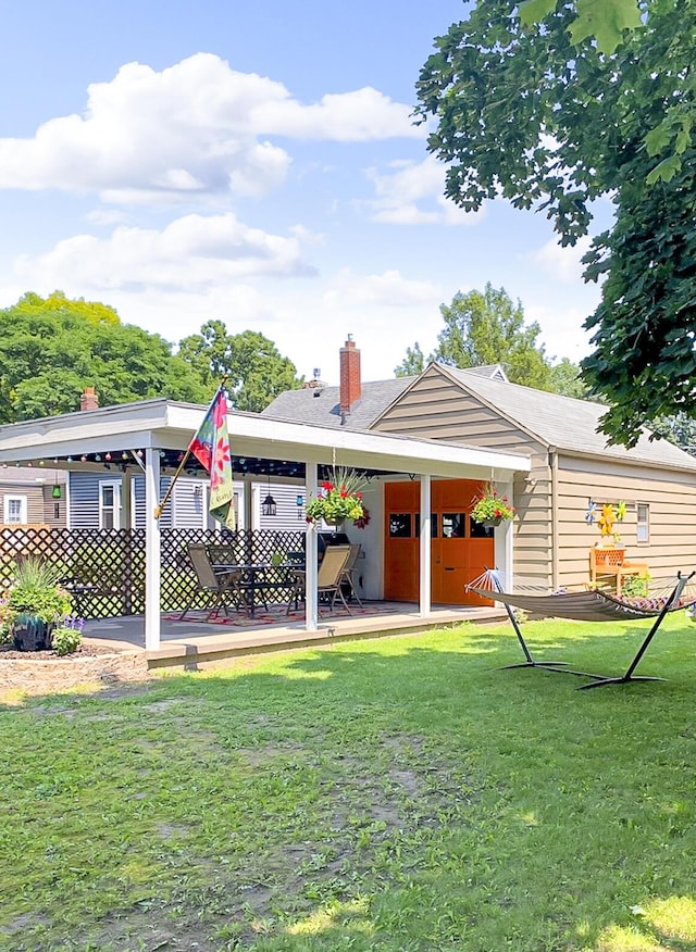 rear view of house with a patio area, a lawn, and a chimney