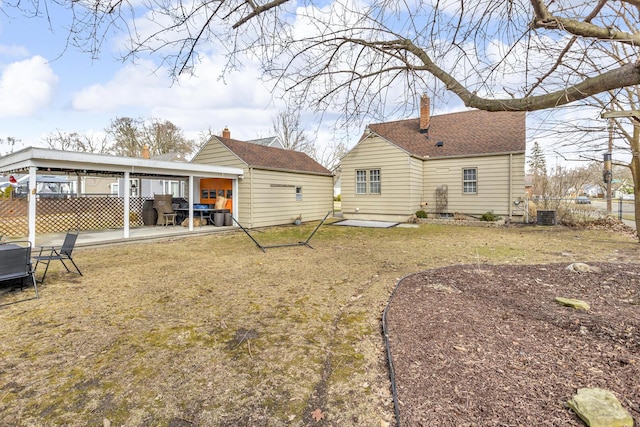 rear view of house with central AC unit, a patio area, fence, and a yard