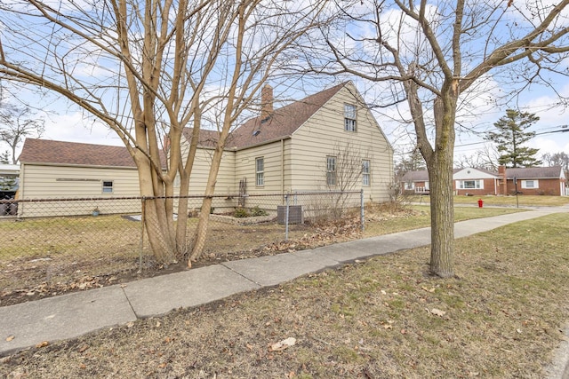 view of home's exterior with a chimney, fence, a lawn, and central AC