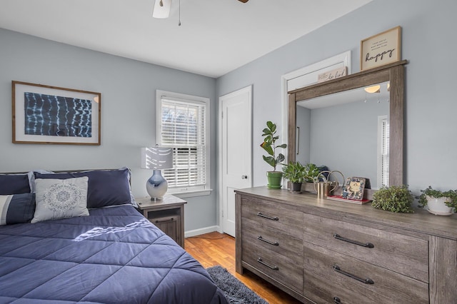 bedroom featuring a ceiling fan, baseboards, and wood finished floors