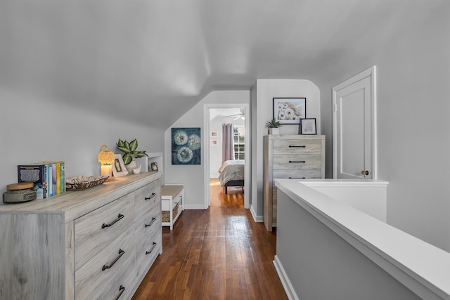 hall with dark wood-style floors, lofted ceiling, and baseboards