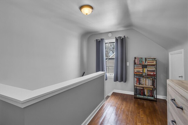 hall featuring lofted ceiling, dark wood-style floors, and baseboards