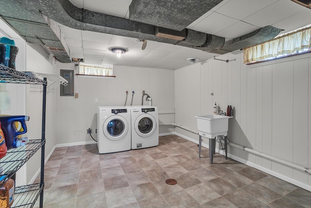 clothes washing area with washer and dryer, laundry area, electric panel, and baseboards