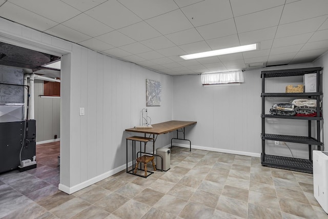 basement featuring a drop ceiling and baseboards