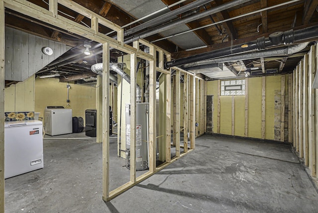 below grade area featuring gas water heater, washing machine and clothes dryer, and refrigerator