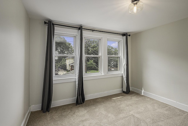 unfurnished room with light carpet, baseboards, and a wealth of natural light