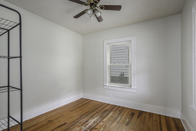 empty room featuring hardwood / wood-style flooring, a ceiling fan, baseboards, and a textured ceiling