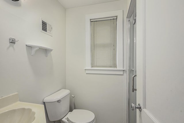 bathroom featuring visible vents, a shower with door, and toilet