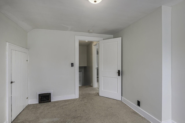 carpeted spare room featuring vaulted ceiling, visible vents, and baseboards