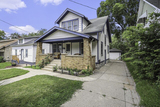 bungalow with brick siding, a detached garage, an outbuilding, covered porch, and a front yard