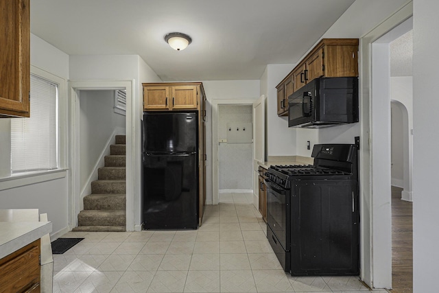 kitchen featuring baseboards, visible vents, arched walkways, brown cabinets, and black appliances