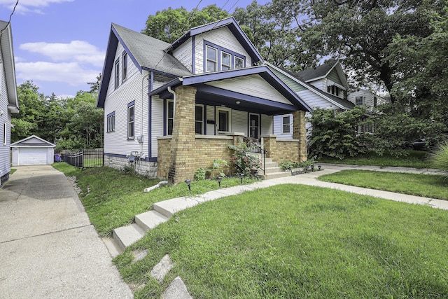 bungalow-style house featuring brick siding, a detached garage, covered porch, an outdoor structure, and a front yard