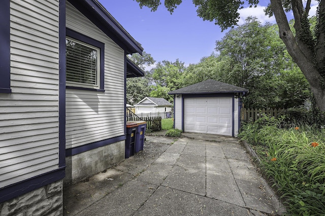 view of property exterior featuring a garage, fence, and an outdoor structure