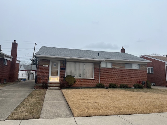 bungalow-style home with a front yard, brick siding, and roof with shingles